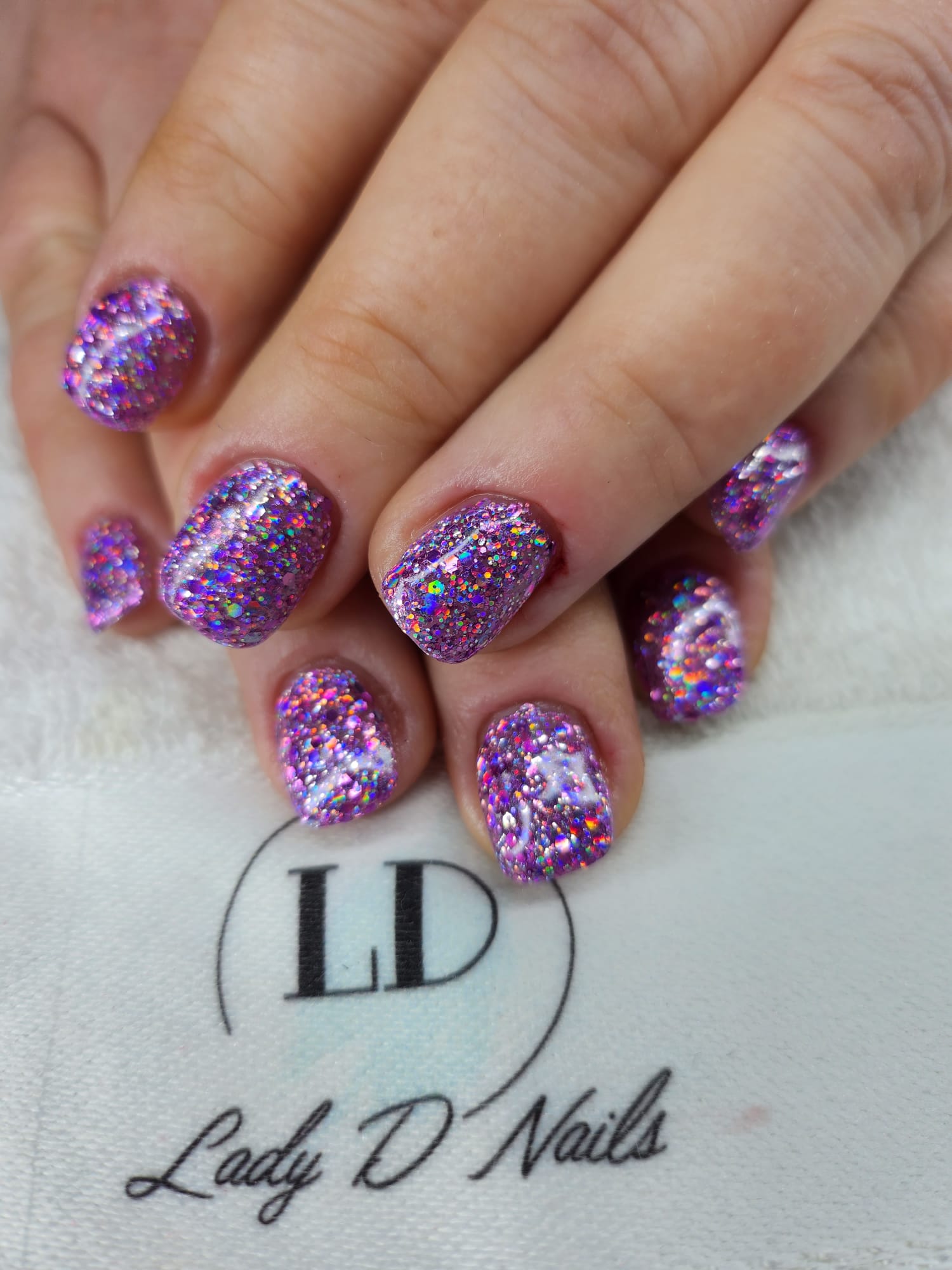 Nägel komplett mit lila holografischem Glitzer bedeckt