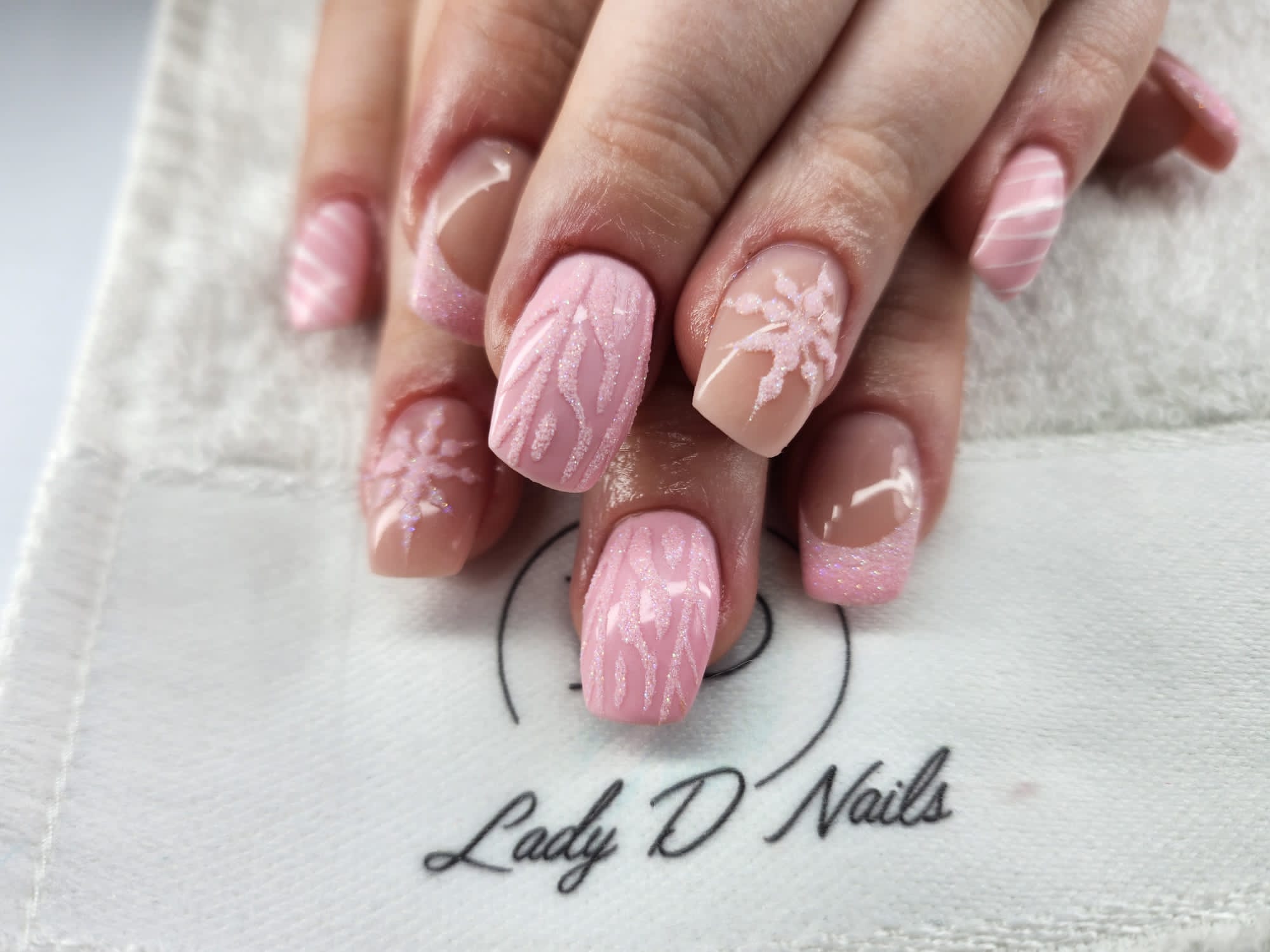 Rosa Nägel mit glitzernden Blütenmotiven und Nude-French