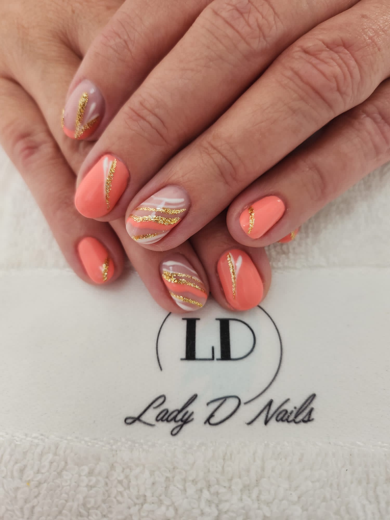Korallfarbene Nägel mit goldenen Glitzerlinien