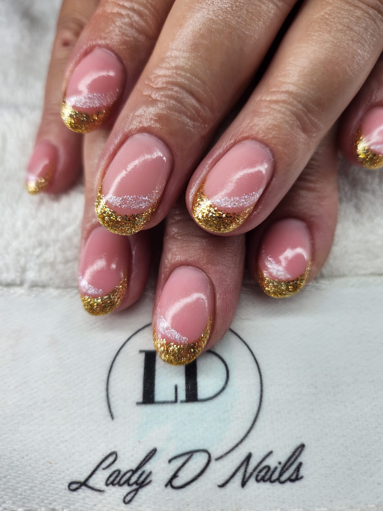 Ovale rosé Nägel mit goldenen Glitzer-French-Spitzen
